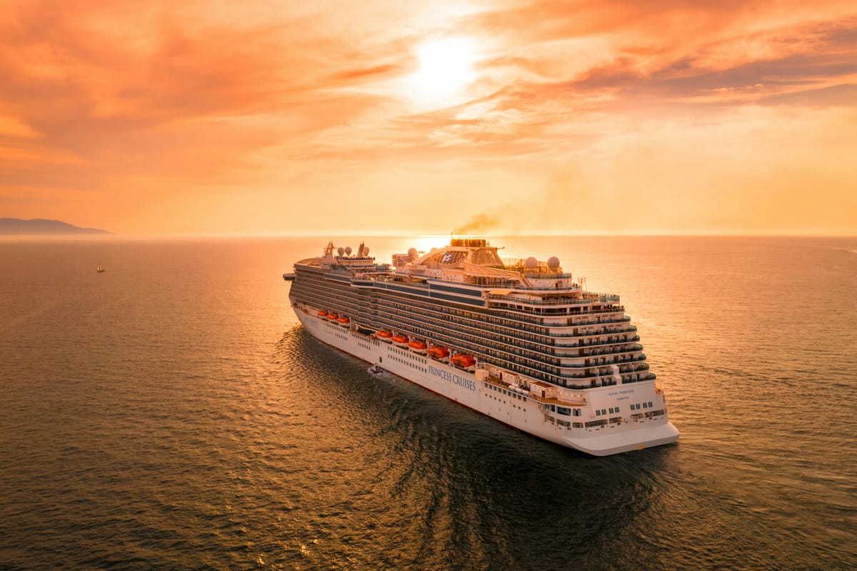 Ein Kreuzfahrtschiff auf ruhiger See im Abendrot.