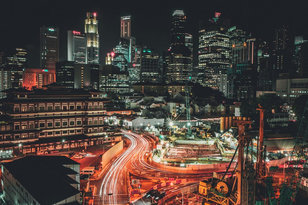 Pulsierende, moderne Großstadt in der Nacht, Verkehrsströme und Wolkenkratzer.